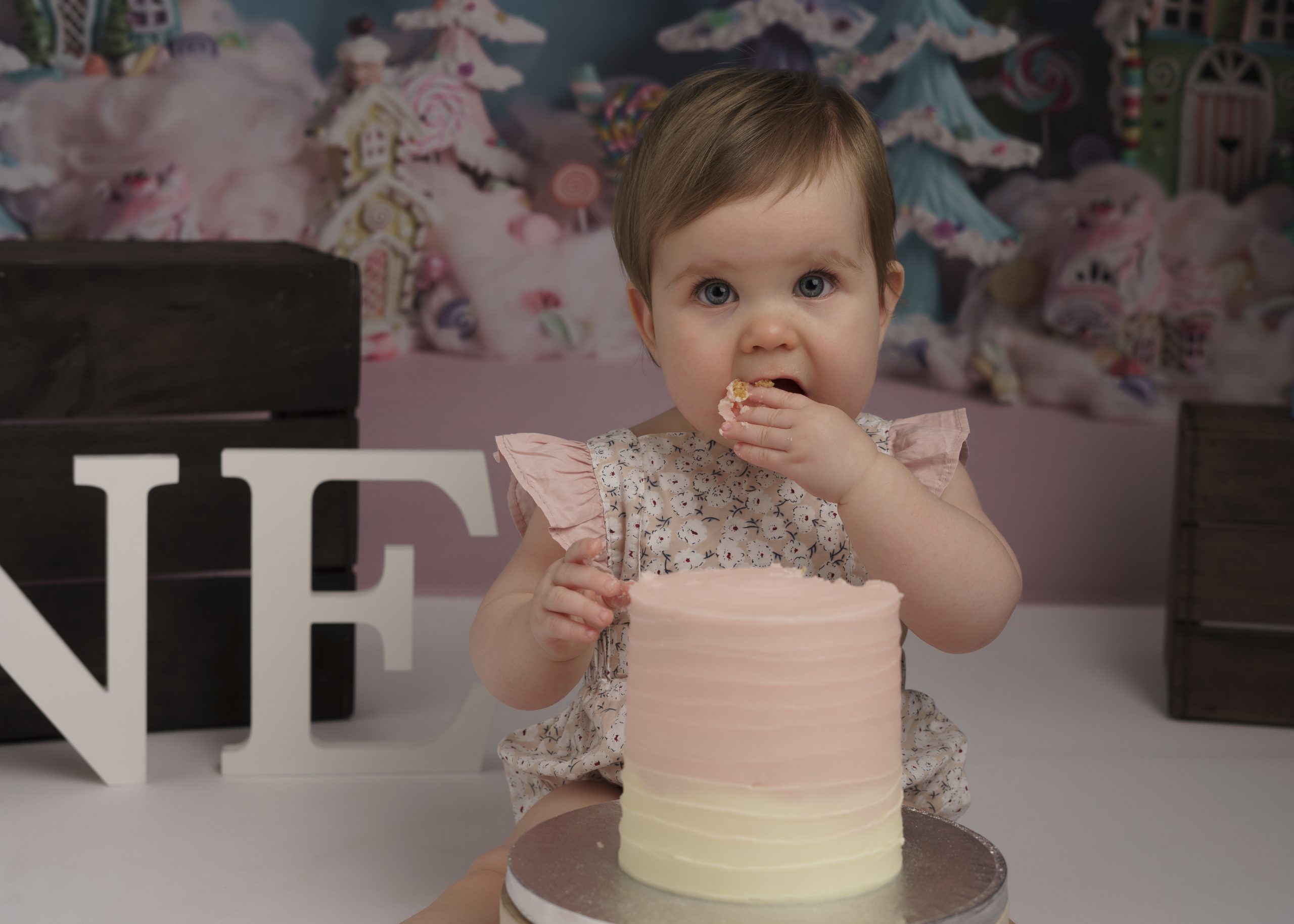 baby girl eating cake at a cake smash session by baby photographer stowmarket