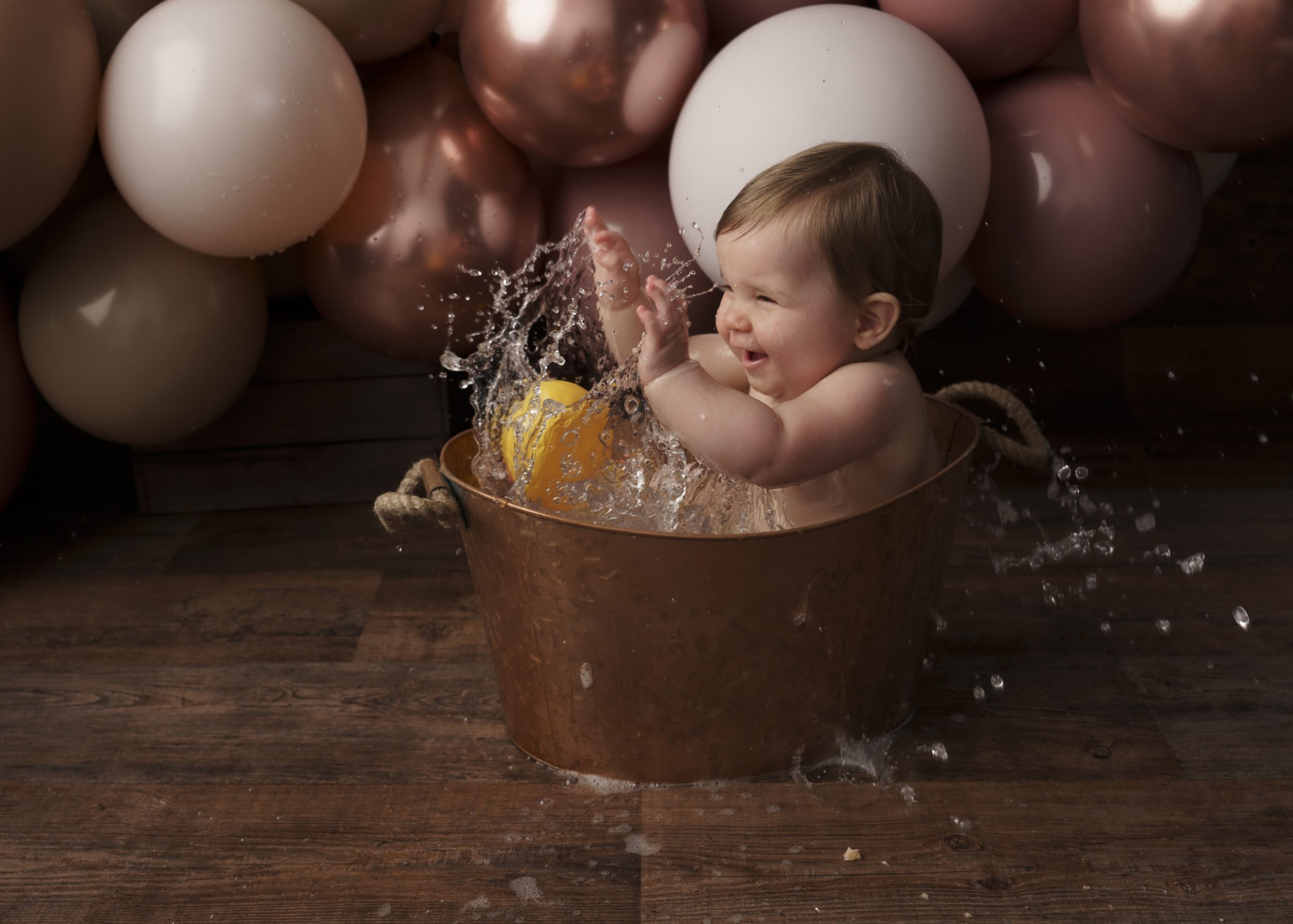 baby girl splashing for cake smash session by baby photographer stowmarket